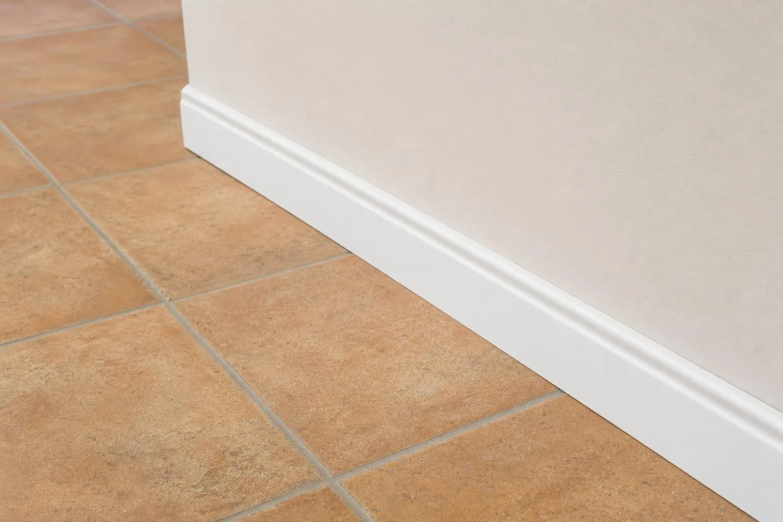 Detalle de suelo nuevo con rodapié blanco junto a pared recién pintada