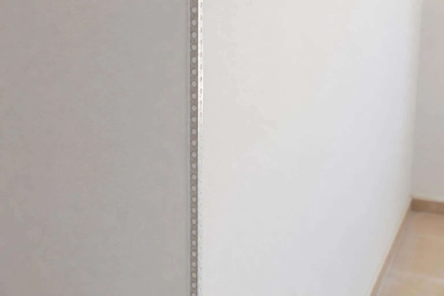 Esquina de pared enlucida con guardavivos metálico