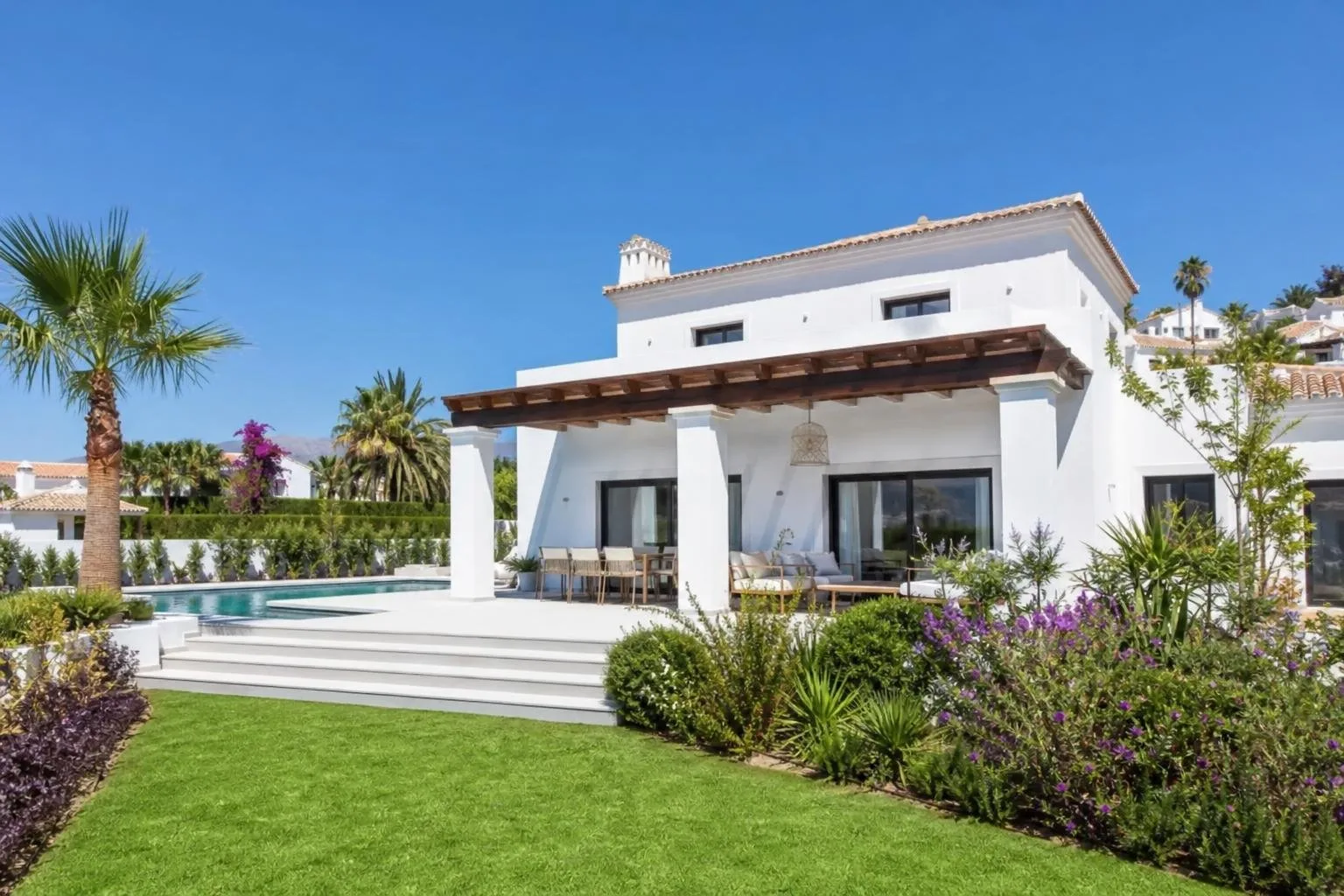 Exterior de villa reformada con fachada blanca y jardín